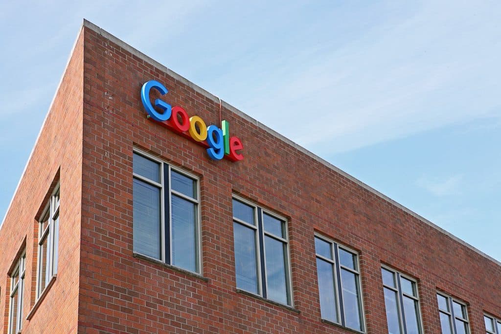 Brick building with the Google logo on the facade, featuring several windows under a clear blue sky.