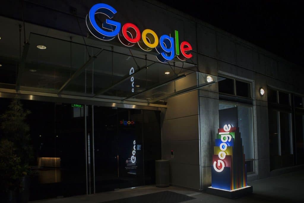 Night view of a building entrance with illuminated Google signs in multiple colors.