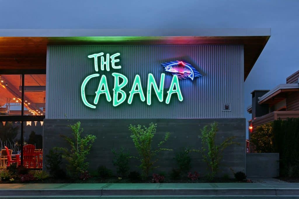 Neon sign reading "The Cabana" on the exterior of a building, with small plants below.