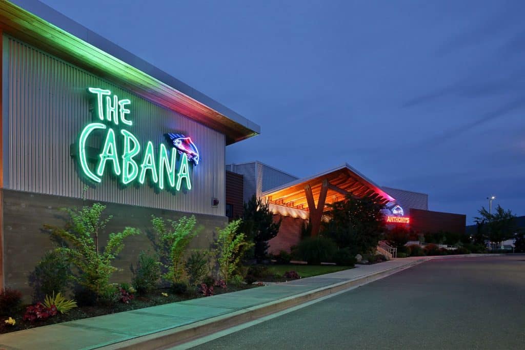 A building with a neon sign reading "The Cabana" and entrance lights at dusk. A driveway and landscaping are visible.