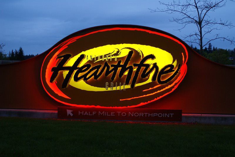 Illuminated sign for Anthony's Hearthfire Grill, with a direction notice for "Half Mile to Northpoint," set against an evening sky.