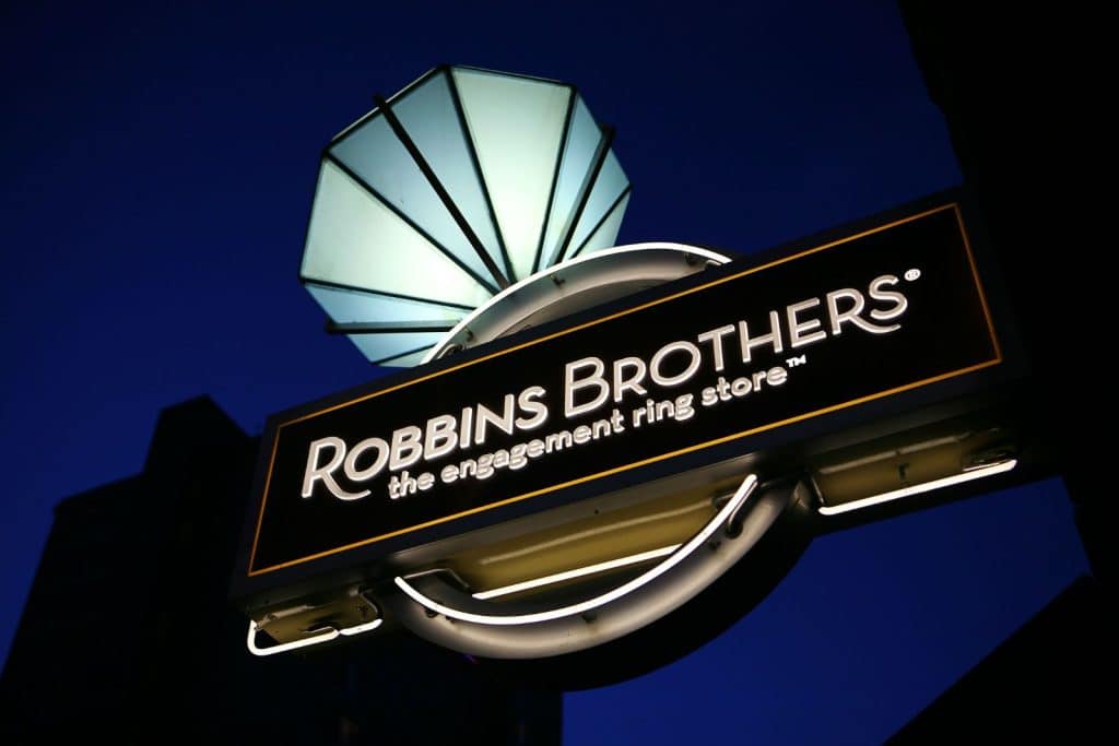 Illuminated Robbins Brothers sign with a diamond ring design against a dark sky.