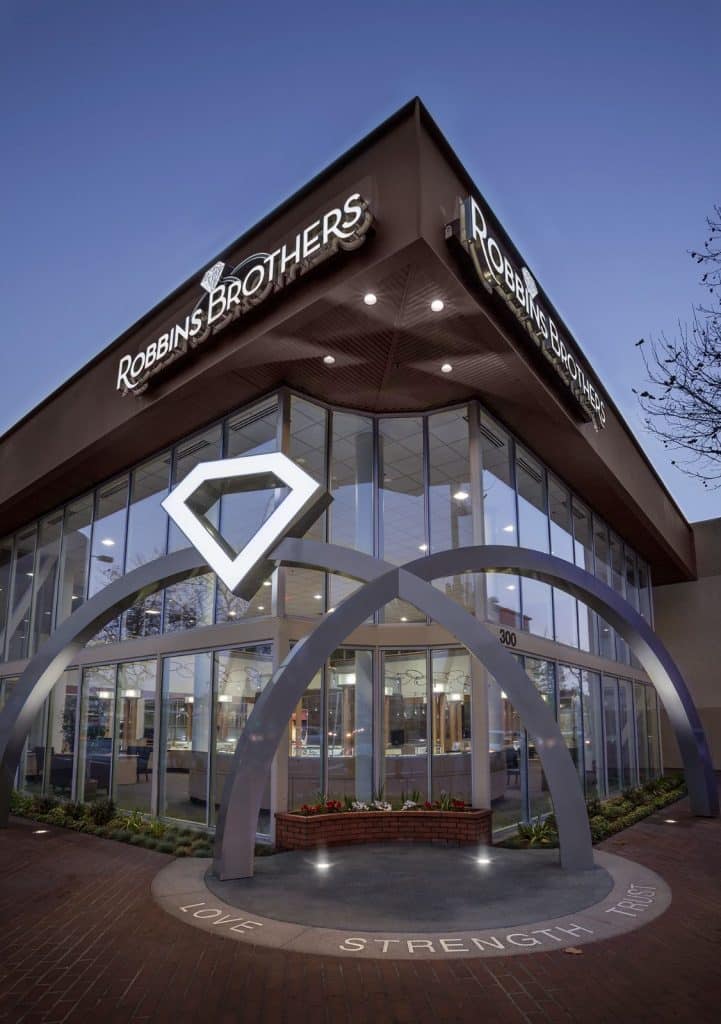 Robbins Brothers jewelry store exterior with large illuminated diamond sign and glass facade at dusk.