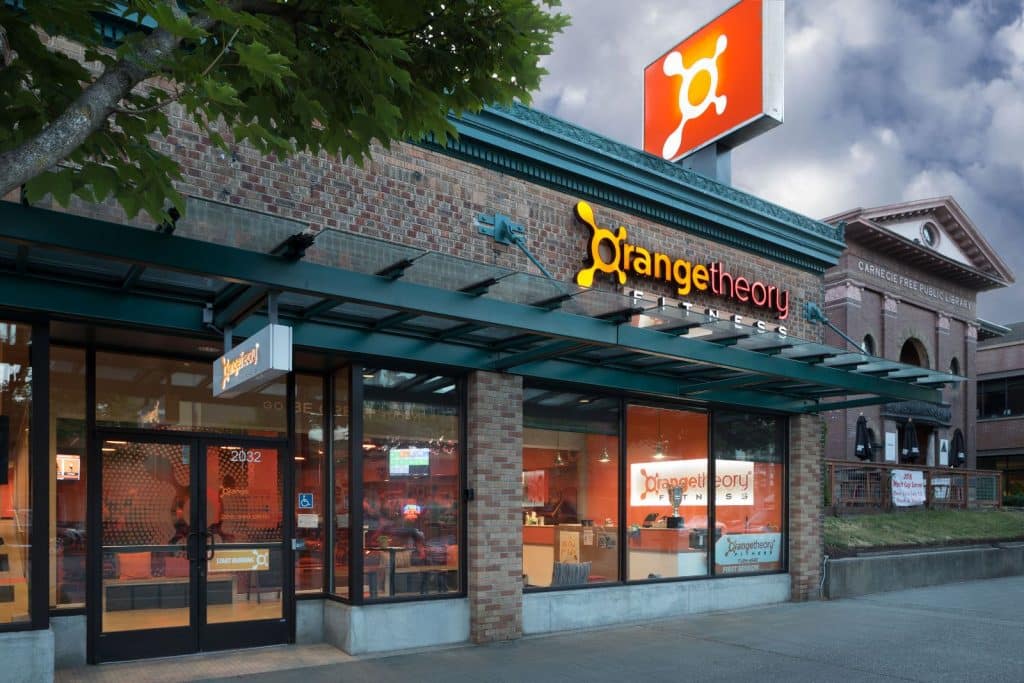 Exterior view of an Orangetheory Fitness location with brick facade and large windows.