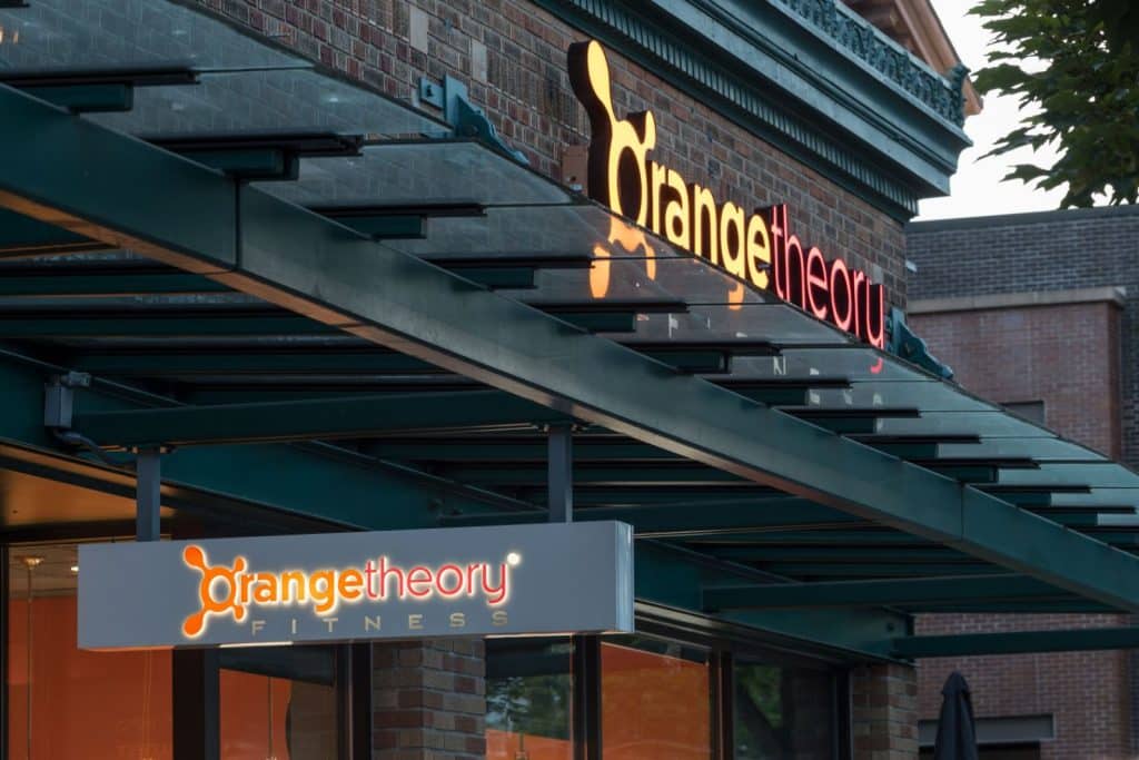 Exterior view of an Orangetheory Fitness gym with illuminated signage.