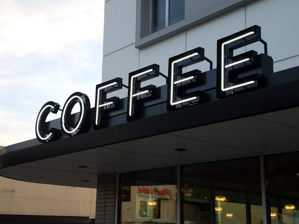 A building facade with a large, illuminated sign reading "COFFEE" in bold letters.