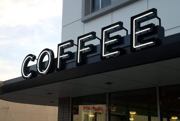 A building facade with a large, illuminated sign reading "COFFEE" in bold letters.