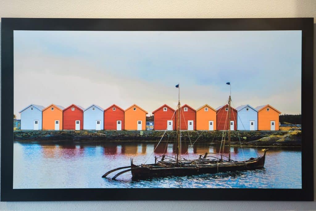 A row of colorful houses lines the waterfront, with a traditional wooden boat floating in the foreground.