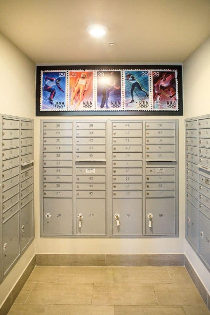 Rows of silver mailboxes with large, colorful stamps depicting athletes above them.