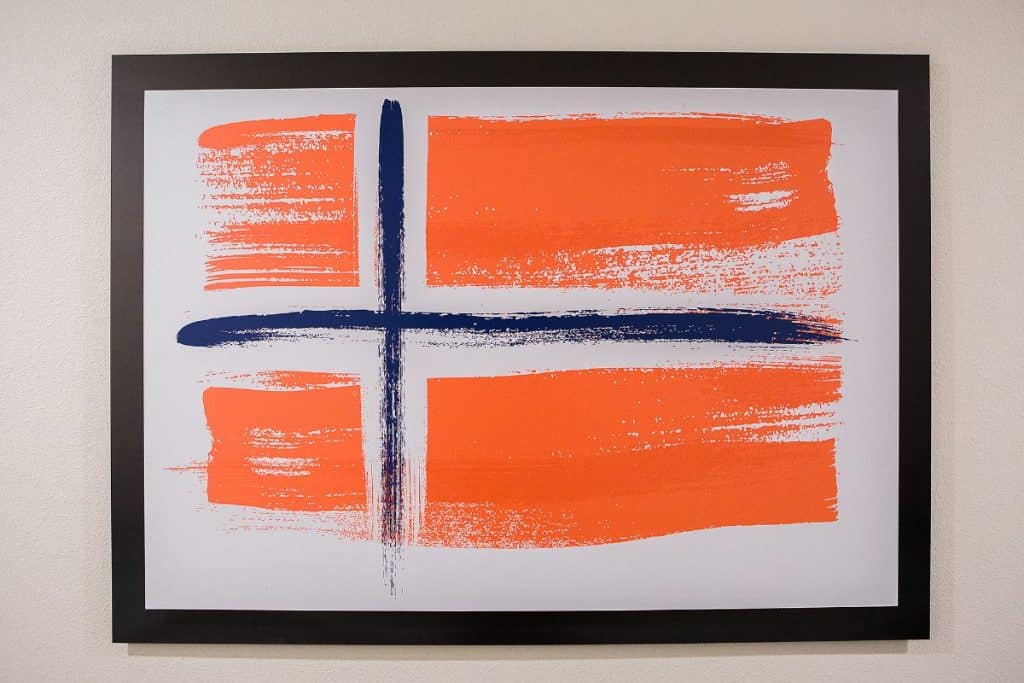 Artwork with an orange background and a blue cross-like shape, framed in black.