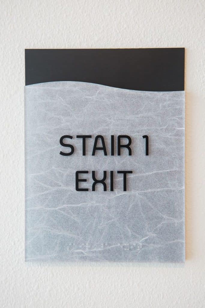 Sign on a textured wall reading "STAIR 1 EXIT" in black text.