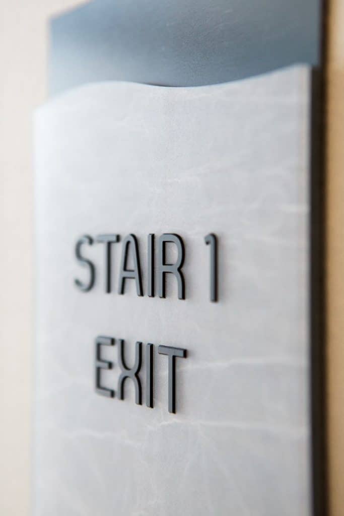 Sign reading "Stair 1 Exit" on a textured gray surface.