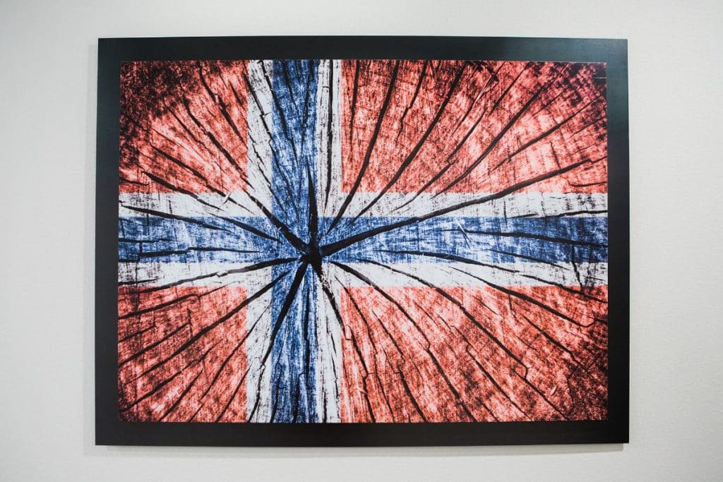 Artwork of a stylized Norwegian flag painted on a wooden texture, framed and hung on a wall.