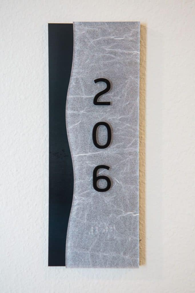 Sign with the number 206, featuring a wavy textured background and a vertical black stripe on the left.