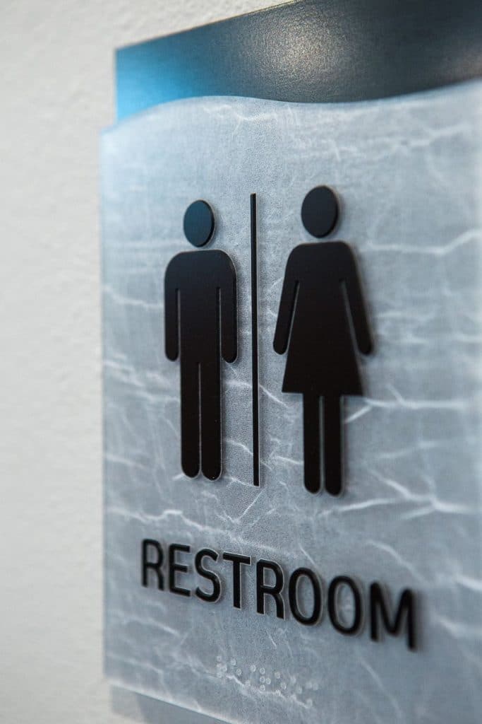 Restroom sign with male and female symbols on a marbled background.