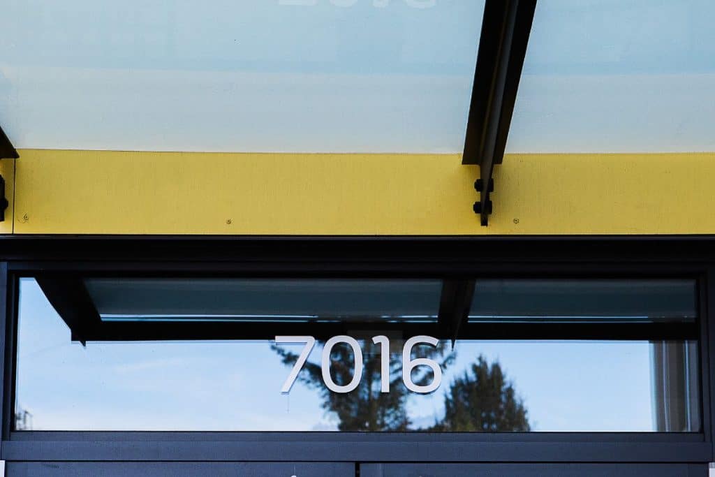 Glass door with the number 7016 displayed above it, under a canopy.