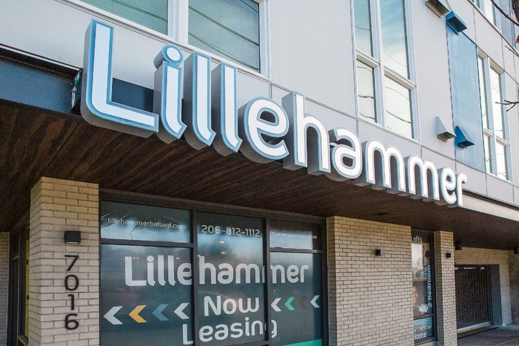 Building facade with a large sign reading "Lillehammer." Below, windows display text: "Lillehammer Now Leasing" with contact details and an address "7016" on the pillar.