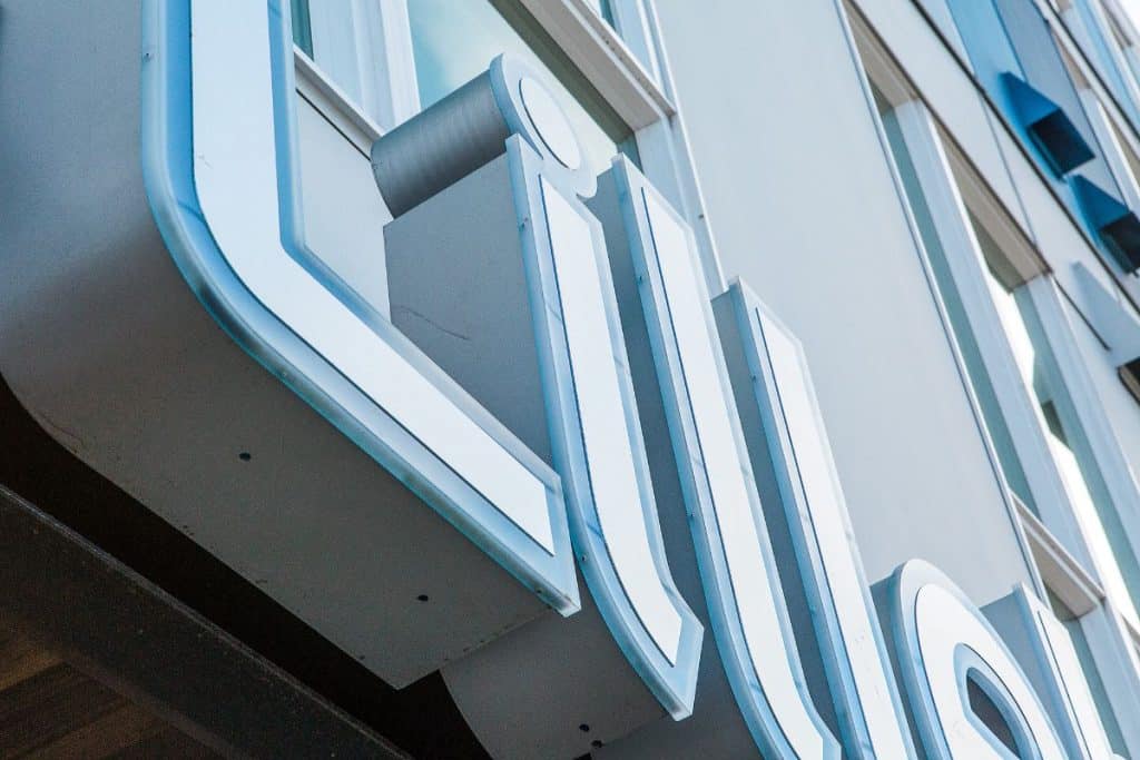 Close-up view of large blue and white sign with letters on the side of a building.