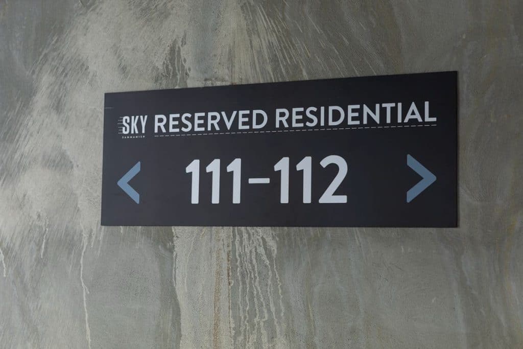 Sign reading "Sky Reserved Residential 111-112" with arrows pointing left and right, mounted on a concrete wall.