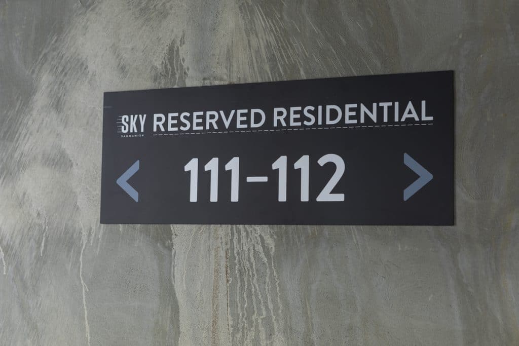 A sign on a concrete wall reads "SKY Reserved Residential" with "111-112" and arrows pointing left and right.