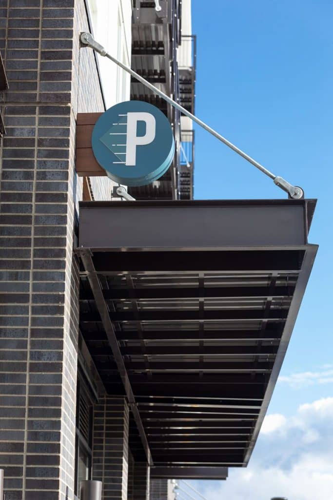 A building facade with a "P" sign hanging above a metal canopy, set against a blue sky.