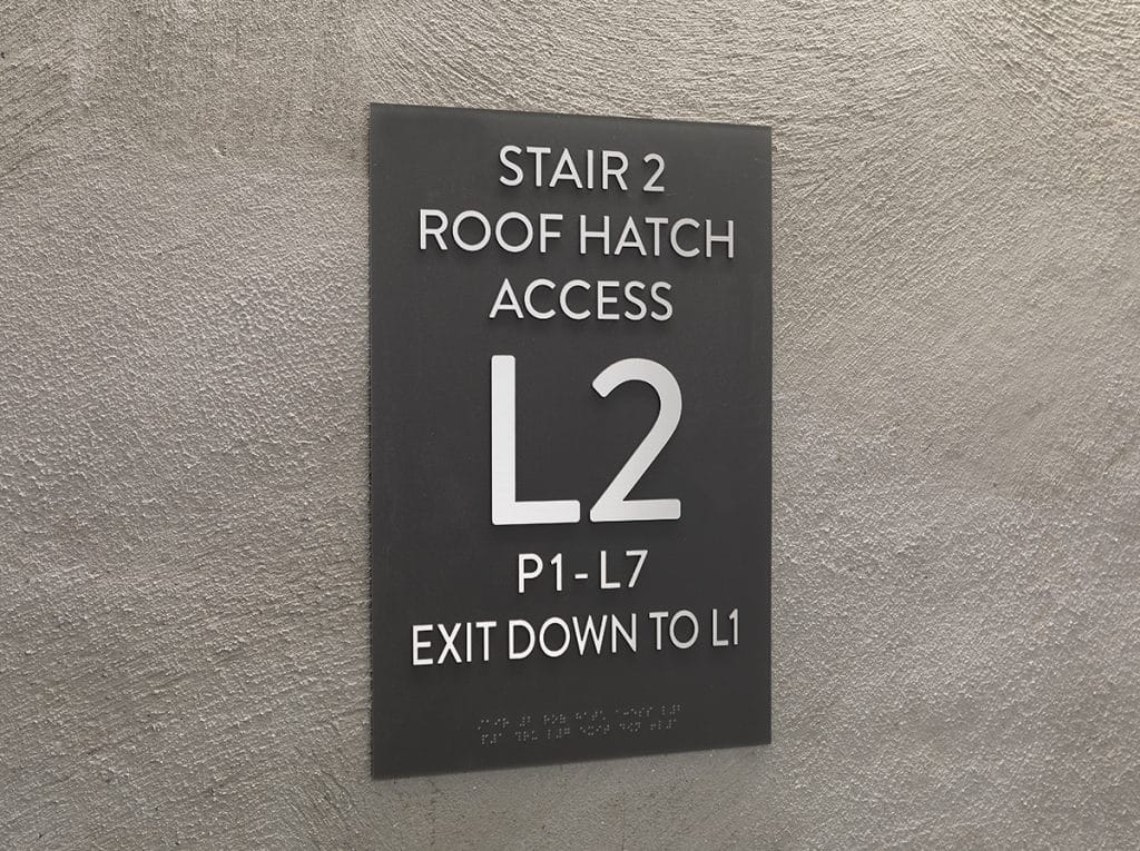 Sign on a textured wall: "Stair 2, Roof Hatch Access, L2, P1-L7, Exit Down to L1.