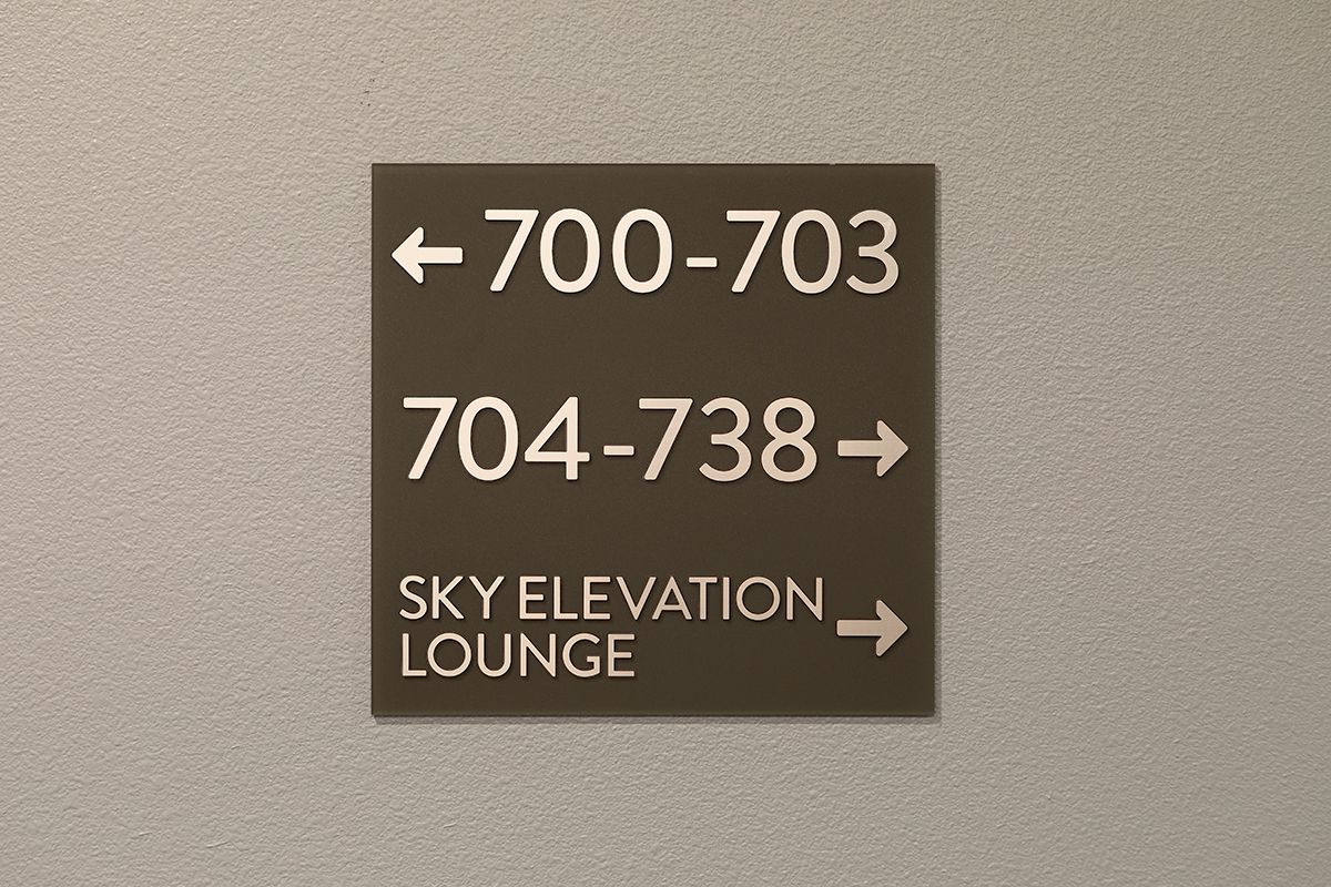 A wall sign with room numbers 700-703 to the left, 704-738 straight ahead, and Sky Elevation Lounge to the right.