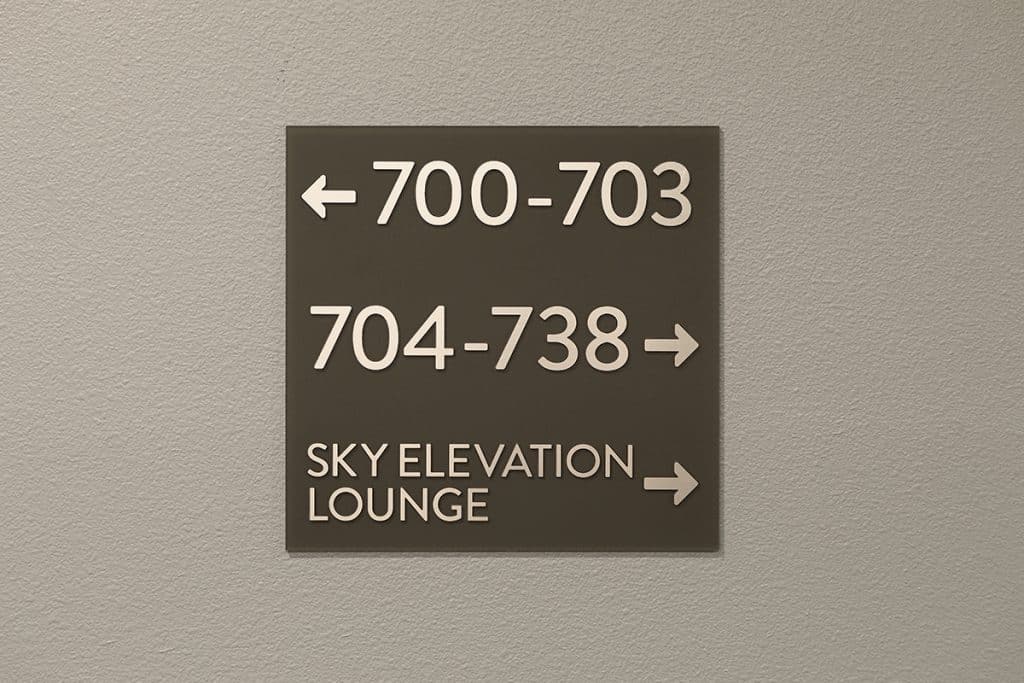 A directional sign on a wall indicating rooms 700-703 to the left, rooms 704-738 to the right, and the Sky Elevation Lounge to the right.