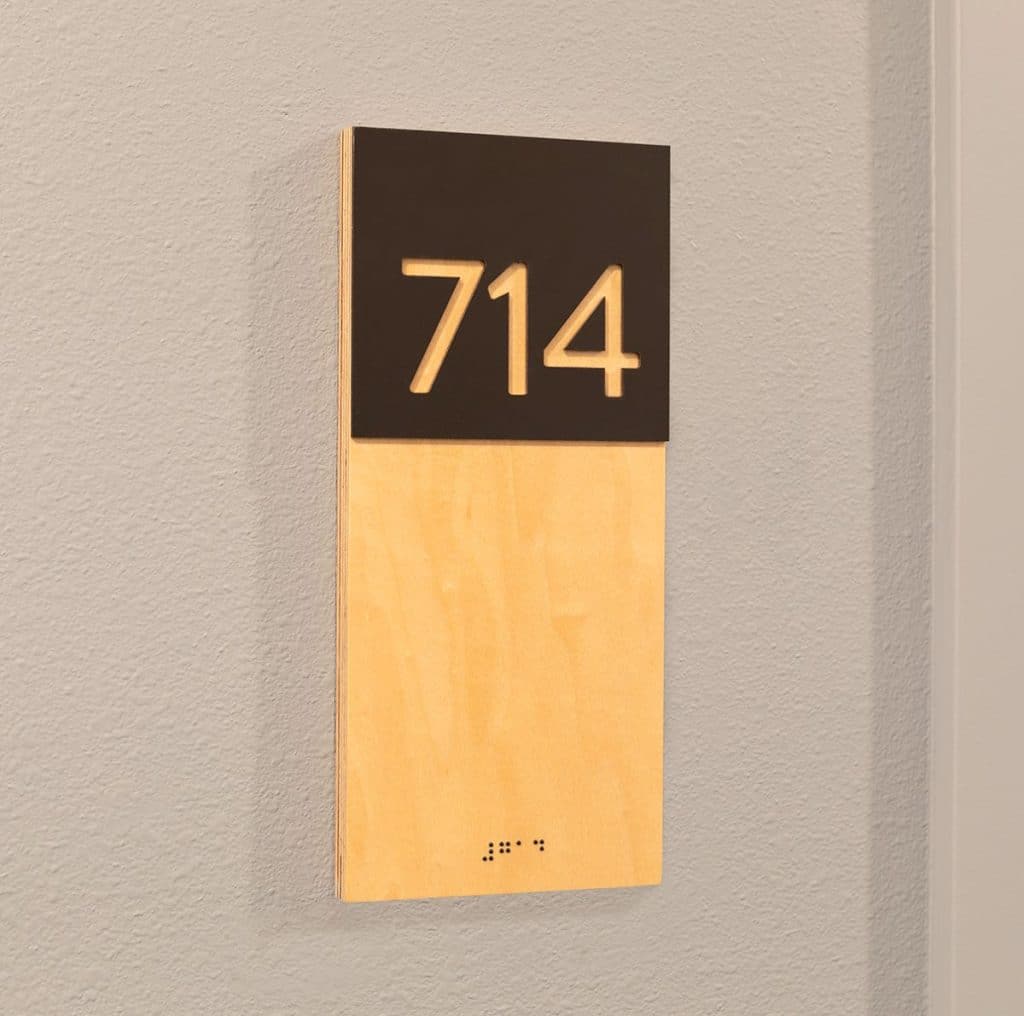 A sign displaying the number 714 with braille beneath it, mounted on a wall.