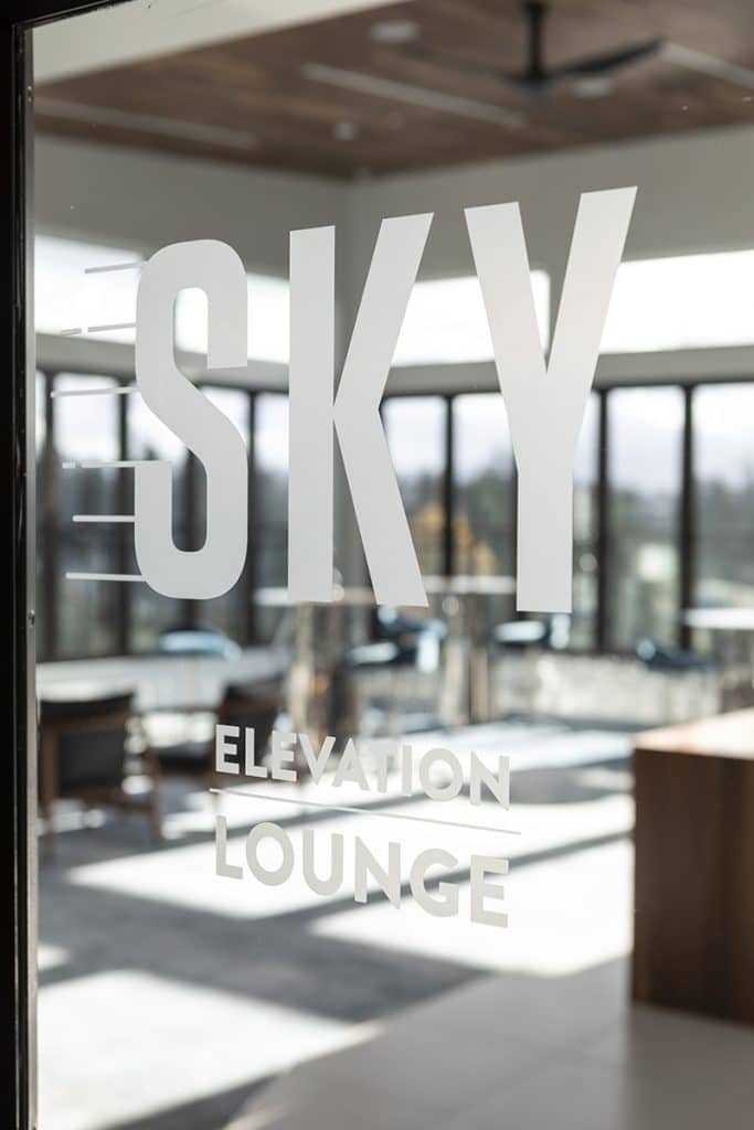 Sign on glass door reading "SKY Elevation Lounge" with a modern interior visible through the glass.