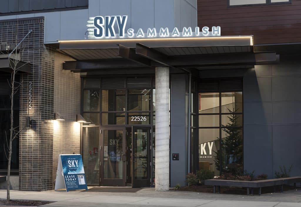 Exterior view of the Sky Sammamish building entrance with illuminated signage and a sidewalk sign.