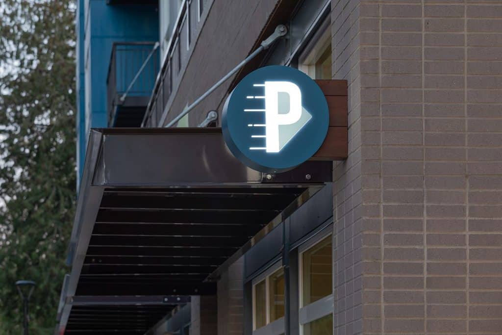 Illuminated parking sign with a white 'P' and a semicircle design on a building exterior.