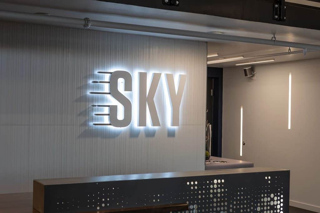 Illuminated "SKY" sign on a modern, minimalist interior wall with subtle lighting accents.