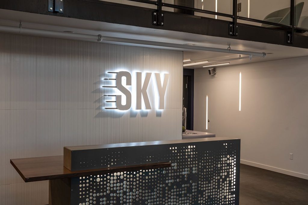 Modern reception area with a front desk and a wall sign reading "SKY" in illuminated letters.