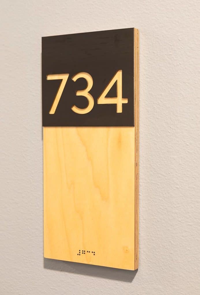 A wooden room number sign displays "734" with Braille below it.