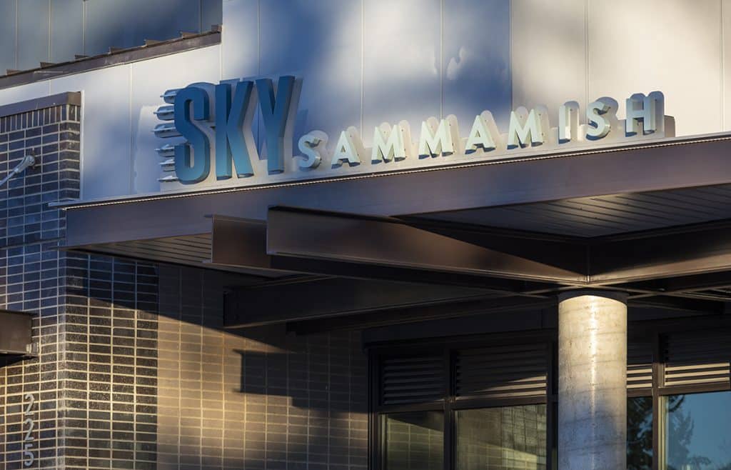 Sign on a building reads "Sky Sammamish" with modern architectural details, featuring brick and metal elements.