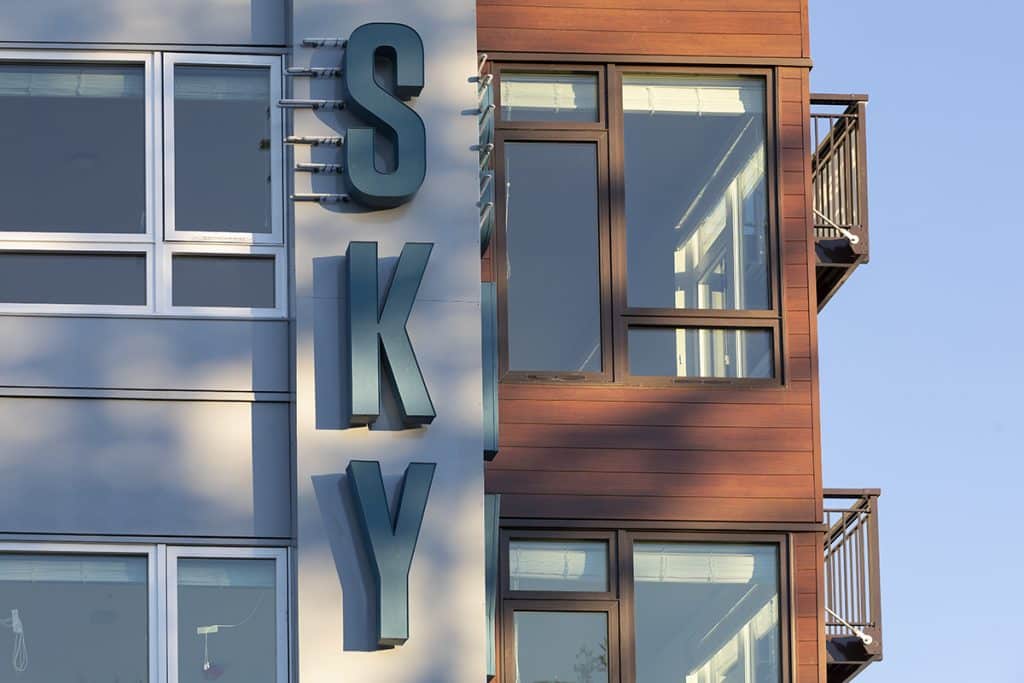 Modern building facade with large windows and a vertical sign displaying the word "SKY" in blue letters.