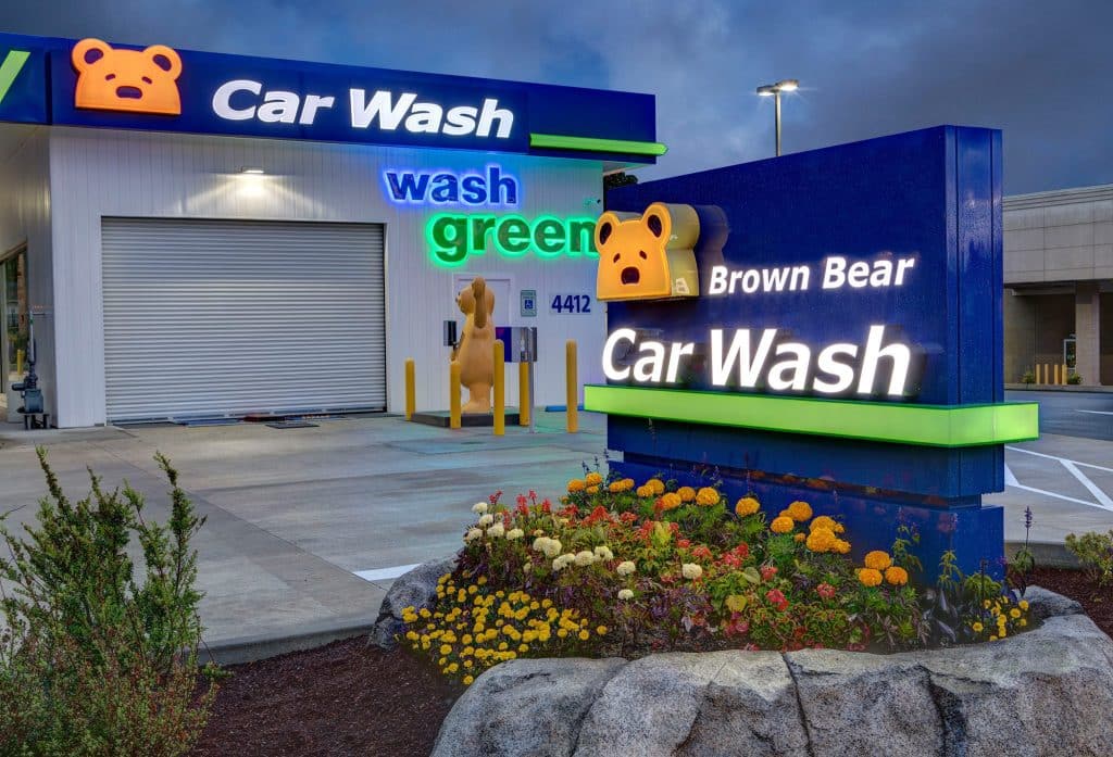 Brown Bear Car Wash with colorful signage and flowered landscaping in the foreground.