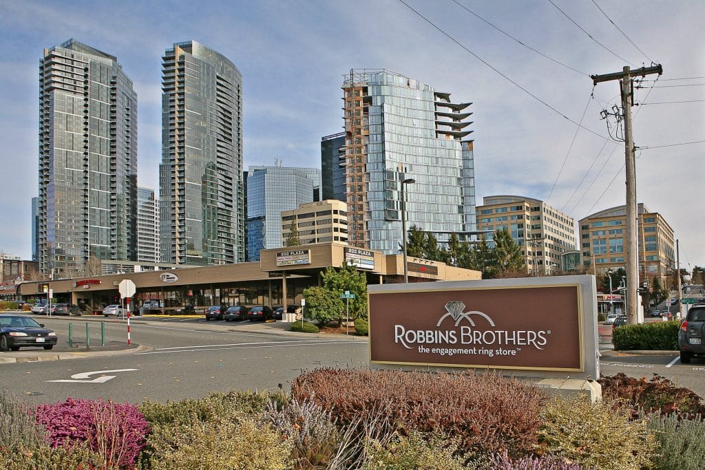 Street view of a shopping area with a Robbins Brothers sign in the foreground. Tall buildings and a clear sky in the background.