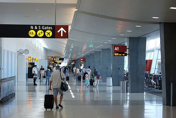 People walking through an airport terminal with signs overhead indicating directions to gates N and S and gate A1.