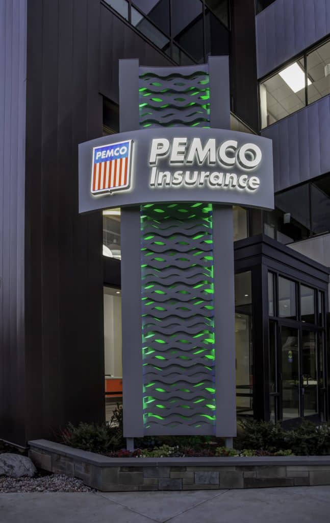 Signage for PEMCO Insurance with illuminated green accents in front of a modern building.