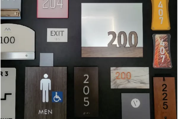 A collage of various door number signs and labels, including "200," "EXIT," and "STAFF ONLY," displayed on a dark background.