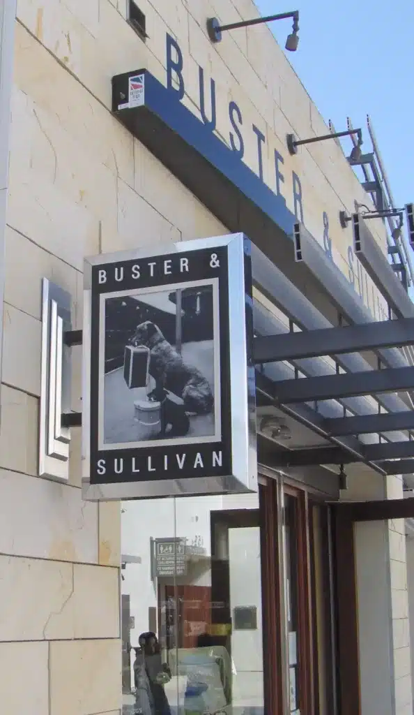 Storefront with a "Buster & Sullivan" sign featuring a black and white image of a dog and a radio.