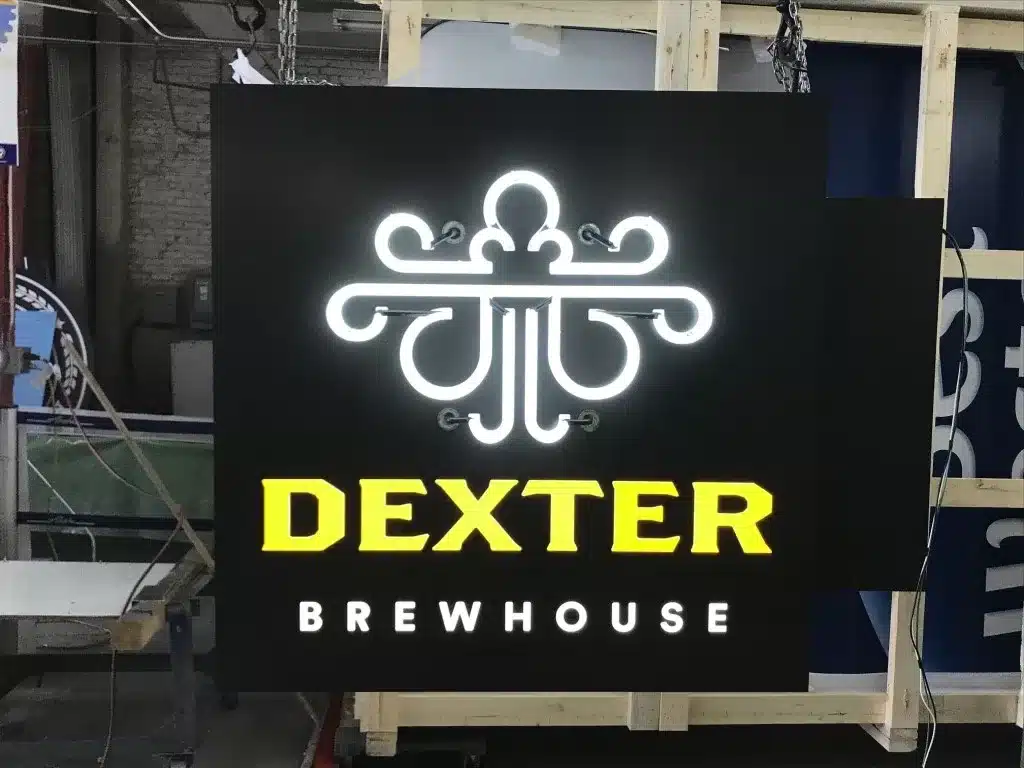 A neon sign with the word "Dexter" in yellow and "Brewhouse" in white below a stylized design on a dark background.