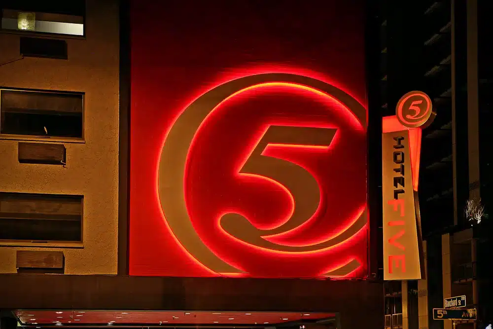 Hotel signage at night featuring a large, illuminated number 5 and the text "HOTEL FIVE" with a circular logo.