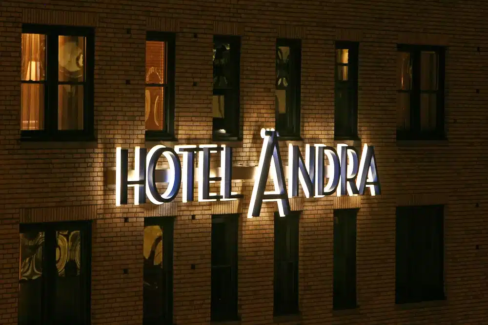 Illuminated "Hotel Ändra" sign on a brick building facade at night.