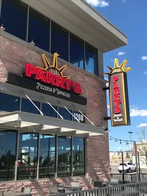 Exterior of Parry's Pizzeria & Taphouse with signage and outdoor seating area under a clear blue sky.