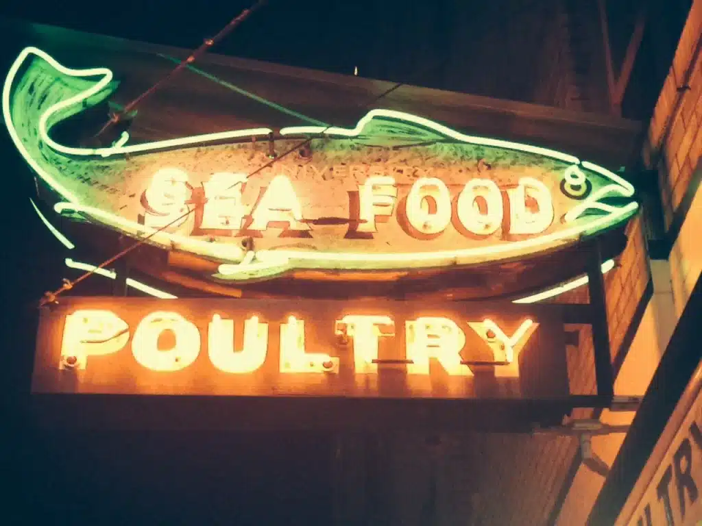 Neon sign of a fish, displaying the words "Sea Food" and "Poultry.