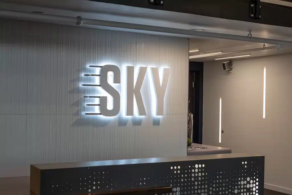 Illuminated logo of "SKY" on a modern interior wall with minimal decor and sleek lighting.