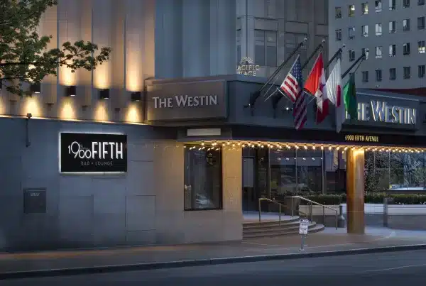 Street view of The Westin hotel with flags displayed above the entrance and a sign for 1900 Fifth Bar + Lounge.